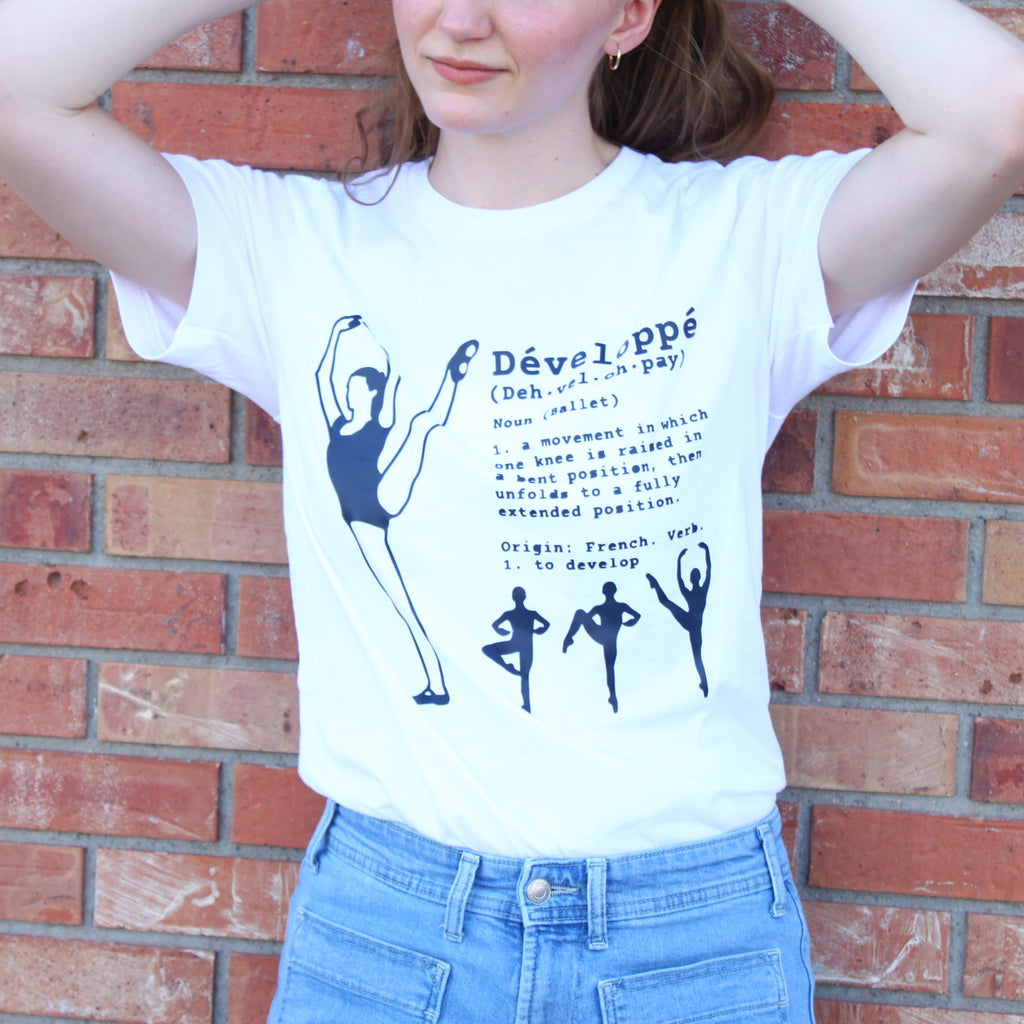 Ballerina performing a developpé a la seconde on T shirt with definition printed in navy blue. Instructions for developpé in ballet