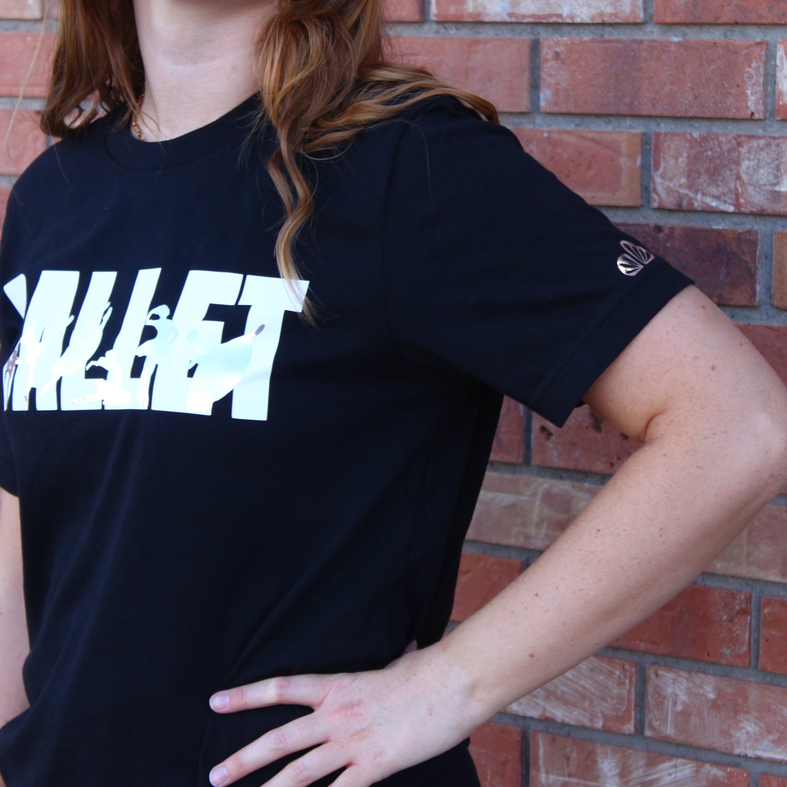 Ballet in white block letters on black t shirt with iconic ballet variations in silver silhouettes. La Esmeralda, Cupid and Kitri from Don Quixote, Dying Swan or Odette from Swan Lake, Raymonda, and Giselle Act 2.