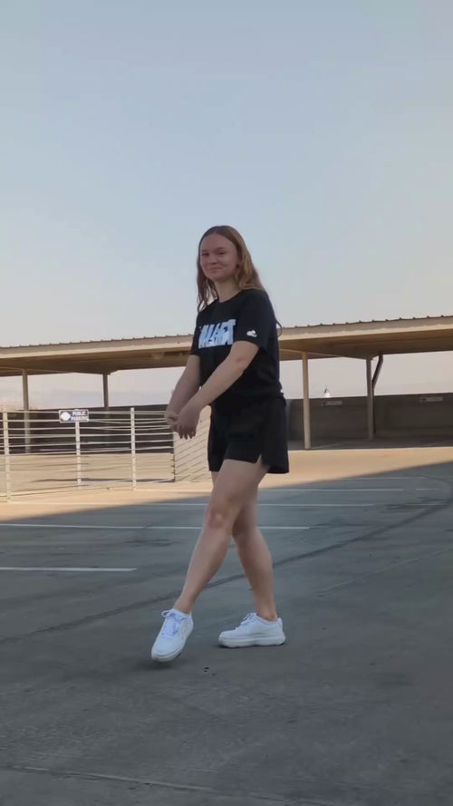 Ballet in white block letters on black t shirt with iconic ballet variations in silver silhouettes. La Esmeralda, Cupid and Kitri from Don Quixote, Dying Swan or Odette from Swan Lake, Raymonda, and Giselle Act 2.
